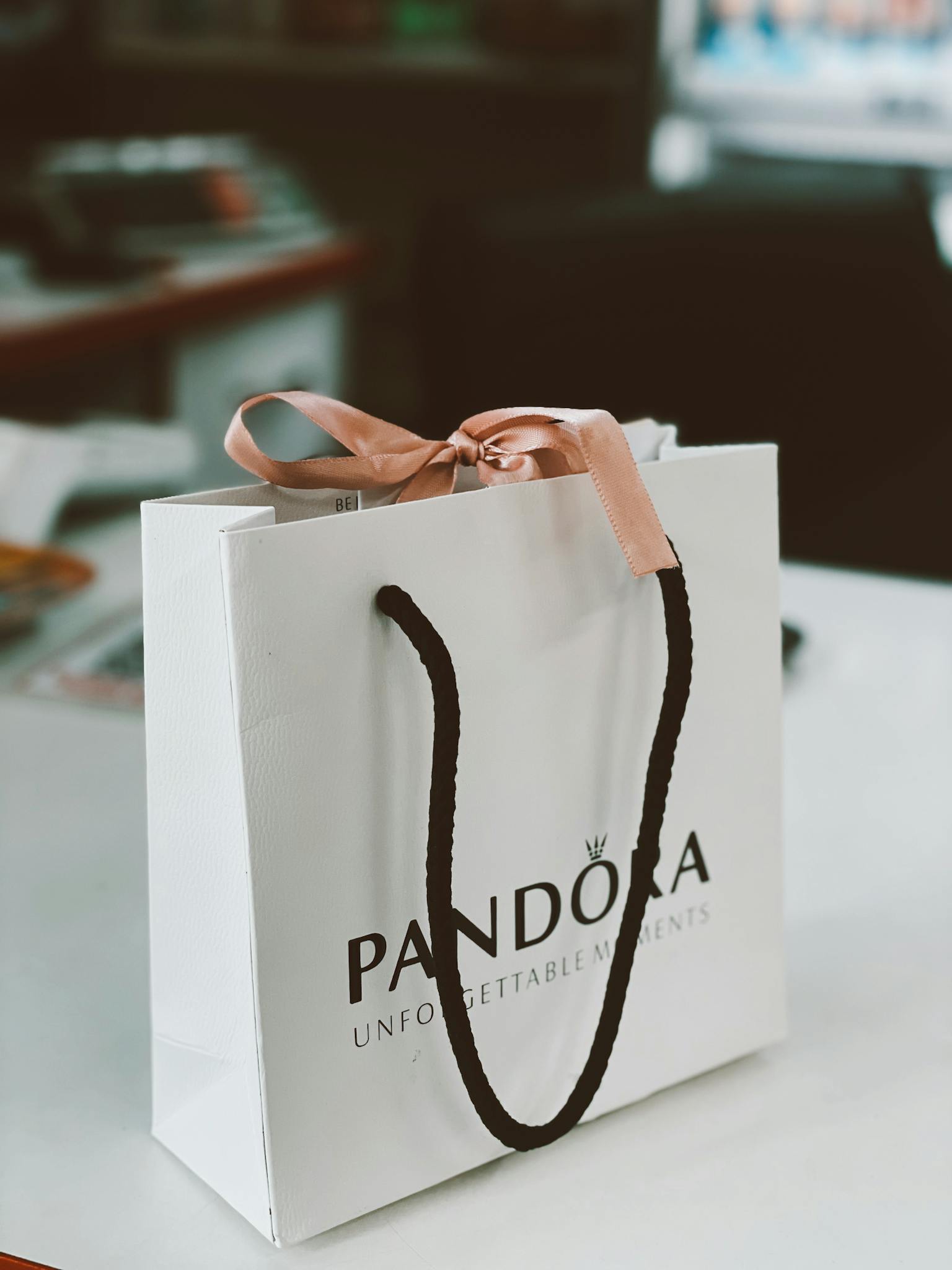 White Pandora shopping bag with elegant handles on a desk.